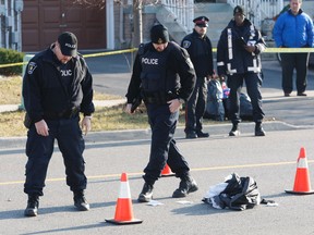 Police investigate the scene where a white van and a pile of clothes from the victim remain after a pedestrian was struck and killed Friday. (MICHAEL PEAKE/Toronto Sun)