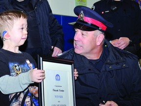 Sgt. Doug Locke of Brockville Police Service presents a Cops Care for Kids plaque to seven-year-old Vincent Norton. Norton won a trip to a WWE event and the Great Wolf Lodge (ALANAH DUFFY/The Recorder and Times).