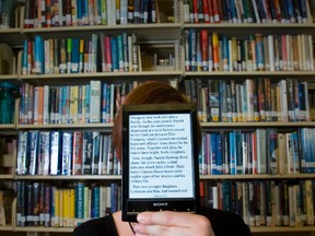 A librarian holds an e-reader. QMI Agency Files