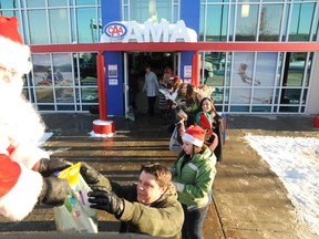 Brock Price passes gifts to Santa, who fills up a truck at the end of a human chain on AMA employees on Friday. The Grande Prairie AMA collected six huge boxes full of toys and food for the Salvation Army during their "Fill Our Fleet, Fill Their Hearts" Christmas campaign Friday, December 14, 2012 in Grande Prairie, Alberta.
PATRICK CALLAN/DAILY HERALD-TRIBUNE/QMI AGENCY