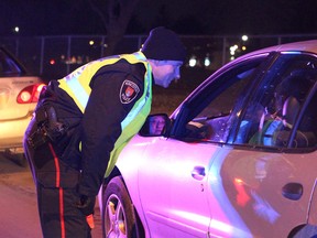 A police officer talks with a driver during a R.I.D.E. check. (Postmedia Network file photo)