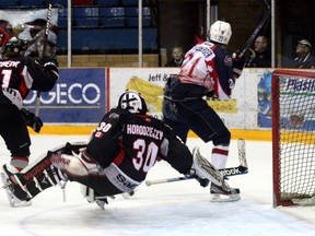 Trappers' Justin Schneeberger knocks Soo Thunderbirds' goaltender Joel Horodziejczyk off his feet during first period action on Sunday.