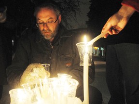 Rev. John Harvey, of St. James Anglican Church, lights some candles at vigil for the Sandy Hook victims Sunday night in Memorial Park.GINO DONATO/THE SUDBURY STAR/QMI AGENCY