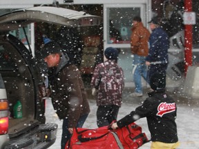 A dad and son get their hockey gear out of the car during a snow squall at the Bell Sensplex in Ottawa Sunday, Dec. 16, 2012. Snow, ice pellets and freezing rain have been falling across the city since Sunday afternoon. Tony Caldwell/Ottawa Sun/QMI Agency
