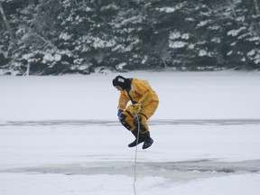 A Kenora firefighter takes the plunge into a hole in the ice to play the victim in a fire department Ice/Water Rescue Training exercise on Lake of the Woods, Saturday, Dec. 15.