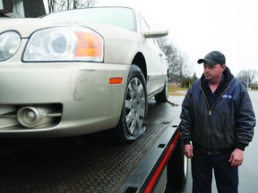 Chris Campbell, of A&R Towing, looks at one of the many cars he had to deal with yesterday in the wake of a mass tire-slashings overnight in Brockville's north-end. (RONALD ZAJAC/The Recorder and Time)
