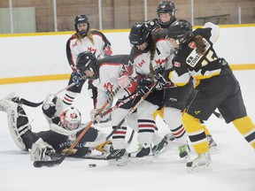 Mitchell’s Maggie McDonnell dives to save the puck as Norfolk forwards Haven Swarts and Emily Thompson dig for it during a bantam B game held in Port Dover on Sunday. Norfolk tied Mitchell 1-1. (SARAH DOKTOR Simcoe Reformer)