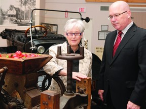 Brockville Museum curator Bonnie Burke shows Leeds-Grenville MPP Steve Clark an apple cider press after a media event at the museum Monday morning. (RONALD ZAJAC/The Recorder and Times)