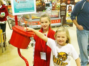 Charisma Hutchinson (left, in uniform) and sister Nevah (putting money in the Kettle) heard that the Salvation Army Kettle was looking for help, she insisted that mom, dad and her sister come out to help.