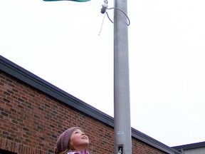 Fabienne Lafrance, 10, lowers the flags in front of Ecole Rose-des-Vents on Tuesday in memory of the 26 victims who lost their lives in Newtown.
Staff photo/ERIKA GLASBERG