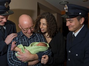 Toronto firefighters Jon Sheppard, left, and David Dey, right, visit Blake Robert Huntley and proud parents Amanda Salzberger and Robert Huntley in their home Tuesday, Dec. 18, 2012. The firefighters helped deliver Blake a week ago. (Dave Thomas/Toronto Sun)