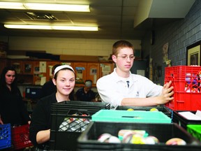 Emily Healey and Sean Fry stack crates of donated food items for two area food banks Wednesday morning at St. Mary Catholic High School. (RONALD ZAJAC/The Recorder and Times)