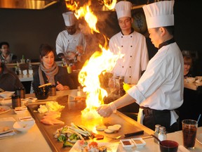 Patrick Callan/Daily Herald-Tribune
Chef Howie Tang lights an onion volcano while preparing lunch  as Wendy Mueller (sitting left) Don Kamieniecki (right) and Sadie Finnebraaten (second from right) look on Sunday at the new Soto Teppanyaki and Fusion Sushi restaurant in the city’s west side.