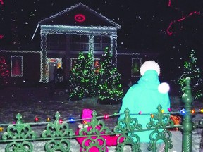 A family stops to gaze at the light show at Crysler Hall, as Christmas Day approaches. 
KATHRYN BURNHAM staff photo