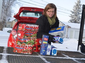 Angela Wilson of Cheyenne Motor Products helps load some of the 450 pounds of food from the back of the Spark into the Melfort Food Bank on Thursday, Dacember 20.