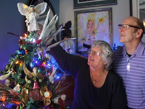 Liz O'Connor, left, adjusts the angel atop her Christmas tree, as her husband, longtime Timmins Police Service officer, Ted, looks on. Liz’s parents got the angel at Christmas when she was just six months old. Along with its centennial celebration, the City of Timmins celebrates 100 years of Christmas memories this holiday season.