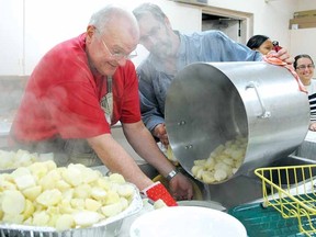Cooks Tom Patterson, left, and Sid Mulder empty a pot of steaming potatoes Christmas Day as they prepare the annual Christmas community dinner at St. James Anglican Church.