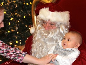 Norman Rockwell, dressed as Santa Claus, holds three-month-old Jacob Davis as his mother gets him to smile for a photo at Peter Pond Mall. JORDAN THOMPSON/TODAY STAFF