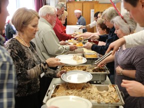 Volunteers serve plates of food at the annual St. Paul’s Anglican Church Christmas Day dinner. (Elliot Ferguson The Whig-Standard)