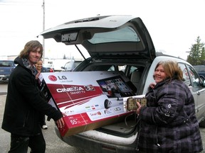 Jody Coture, right, says she can do away with her computer now that her new 3D TV browses the web. She was one of a steady flow of shoppers who bought mostly TVs starting at 6 a.m. Boxing Day. Brick employee David Jackson helps fit the big screen TV into her van.