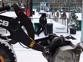 Two police officers pass a City of Edmonton front end loader as the driver works to clear snow at Churchill Square in Edmonton, Alta. on Dec. 26, 2012. The Capital City received a dusting of snow on Boxing Day. Ian Kucerak/Edmonton Sun/QMI Agency