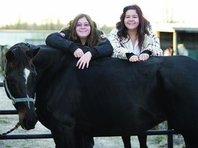 Identical twins Kourteney (right) and Kaitlynn Lappan, who are autistic, pose with Kourteney's horse River. The two girls discovered their talent for showing horses this summer.