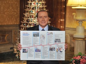 Former Italian PM Silvio Berlusconi holds a card that highlights the actions undertook by the government under his rule from 2001 to 2011 at his residence in Rome December 22, 2012.   REUTERS/Press Officer People of Freedom (PDL) Party/Handout
