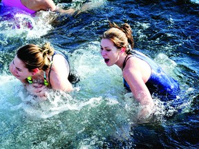 Heidi Gross, left, and Phoenix Tamm surface from the frigid water of the St. Lawrence River during the Freezin' For A Reason Polar Bear Plunge.