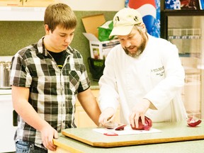 Chef Devon Tabor shows Tanner Steffler how to chop an onion during a cooking demonstration on Dec. 19 at the Vanastra Christian Church.