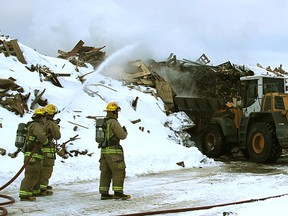 Kingston East firefighters pour water on a large smouldering pile of wood at Norterra Organics on Joyceville Road Wednesday morning as a front-end loader tried to disperse the burning mound.
Michael Lea The Whig-Standard