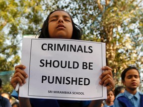 Schoolgirls pray to pay homage to a rape victim who was assaulted in New Delhi, at a school in the western Indian city of Ahmedabad in this December 29, 2012 file photo. Beaten and raped by five men and a teenager on a moving bus in the capital on Dec. 16, a 23-year-old student died from her injuries on Dec. 29 which resulted in thousands of outraged young Indians taking to the streets of New Delhi almost every day protesting for justice and security for women. India's politicians, seen as out of touch with the aspirations of the urban middle class, have been caught off guard by the protests. (REUTERS/Amit Dave/File)