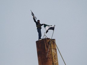 A member of the Free Syrian Army fires his weapon after lowering a Syrian flag and raising a Syrian opposition flag near the Turkish border in the northern Syrian town of Ras al-Ain. NATO's plans to deploy Patriot missiles along the border sends a clear message to the Assad regime: The West is against you.