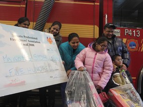 After losing everything in a house fire, a Toronto family was given $500 by the Toronto Professional Fire Fighters' Association on Thursday. Mother Sukhwinder Sidhu (in blue jacket), father Shyam Sidhu (in glasses), and their two children Jasmine, 8, and Anvir, 6. (Maryam Shah/Toronto Sun)