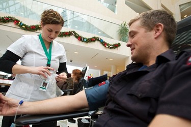 Cameron Haugrud (right), an Edmonton Fire Rescue Services firefighter with Station 11, donates blood for the first time at Edmonton City Hall on Jan. 4, 2013, during the Sirens for Life challenge, which pits emergency services personnel in Edmonton and Calgary against each other in a friendly competition to increase blood donations. The goal in Edmonton is to collect 5,000 units of blood in Edmonton this month to beat Calgary's total. Ian Kucerak/Edmonton Sun/QMI Agency