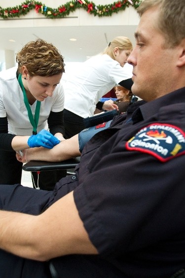 Phlebotomist Allissa Keane (left) inserts a needle into Edmonton Fire Rescue Services firefighter Cameron Haugrud's arm during a blood drive at Edmonton City Hall on Jan. 4, 2013, during the Sirens for Life challenge, which pits emergency services personnel in Edmonton and Calgary against each other in a friendly competition to increase blood donations. The goal in Edmonton is to collect 5,000 units of blood in Edmonton, to beat Calgary's total. Ian Kucerak/Edmonton Sun/QMI Agency