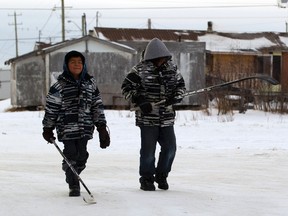 Two young boys walk past substandard housing on their way to play hockey in Attawapiskat in December 2011. 
FRANK GUNN/REUTERS FILES