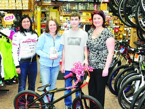 Tammy McCarthy from Gearheads in Petawawa, left, joins Lindsey Cupelli and Kathy Perras, right, in presenting Petawawa teen Chad Wilson-Morrison with a brand new bike, purchased with money raised by the community after word spread that his old bike, a gift from his late father, was stolen in November.