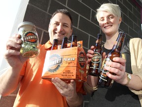 Chris Warwaruk of Farmery Estate Brewery (left) and Farmery public-relations representative Adriana King show off bottles of the locally-sourced beer and hops outside the Southdale Liquor Mart store in Winnipeg, Man., on Saturday, Jan. 5, 2013. (Jason Halstead/Winnipeg Sun)
