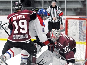Chatham Maroons goalie Scott Tricker makes a save while teammate Blayne Oliver hits Strathroy Rockets' Adam Vandersluis in the third period Sunday at Memorial Arena. (MARK MALONE/The Daily News)