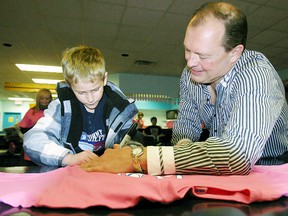 Ryan Murphy, 7, a leukemia survivor, autographs a pink T-shirt for Mayor Al McDonald during the Knockdown for Cancer campaign, Saturday at Partners Billiards and Bowling. The campaign to raise money for the Canadian Cancer Society continues through January. (MARIA CALABRESE The Nugget)