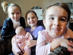 Eight-year-old Modestie Primeau, centre, sits holding her one-month-old sister Braylee,  flanked by sister Serenity, 7, left, and Jayce-Lynne, 2. Primeau grabbed her baby sister, and ushered her other sisters out of their home when I fire broke out in their duplex. She also alerted her grandmother and two young aunts who lived on the other side of the building.  Photo Taken Chatham, On., Monday January 07, 2013. (DIANA MARTIN, The Chatham Daily News)