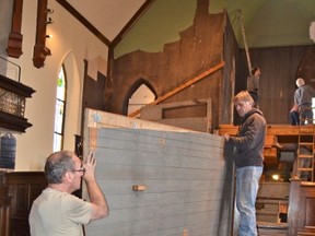 Frank Greaves, left, and Dan Reid remove a wooden panel that housed part of the disassembled Casavant organ in the sanctuary at the former Knox United Church building, now called Harmony Centre Owen Sound, Tuesday.