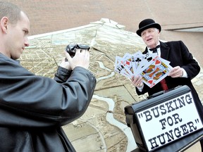 Jeff Hopman, left, films his father, Marien, as he performs magic in front of the Sears in downtown Chatham, to promote their upcoming busking tour to raise money and awareness for Chatham Outreach for Hunger. (DIANA MARTIN, The Chatham Daily News)