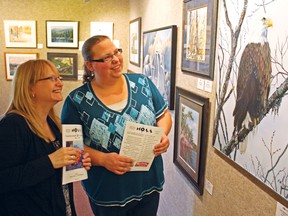 Centre Culturel La Ronde secretary Lorraine Boulanger, left, and event co-ordinator Melanie Bennett admire a painting by Timmins artist Gary Bostrom at the centre's Galleruche art gallery. La Ronde will house the Northern Ontario Art Association's 56th annual art exhibition for entire month of January, with the grand opening this Thursday, Jan. 10 at 7 p.m.