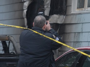 A city police officer takes photographs at the scene of a suspicious fire at 315 Patrick St., on Wednesday, Jan. 9, 2013.