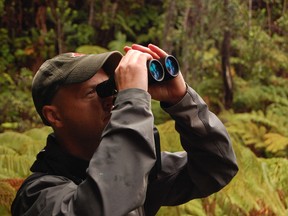 Author and traveling lecturer Chris Fisher takes a look through binoculars at the volcanoes at Hawaii Volcanoes National Park. PHOTO SUPPLIED