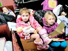 Modestie, 8, back left, Jayce-Lynne, 2, listen to Serenity Primeau, 7, read cards from classmates while perched on bags of donations piled in their grandmother's house from the community. The family suffered a devastating fire on Saturday and have been overwhelmed by the generosity of the community and London woman Janette Cameron. (DIANA MARTIN, The Chatham Daily News)