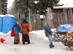 A man pulls a wagon full of wood as people look on in front of the area where Attawapiskat First Nation Chief Theresa Spence is holding her hunger strike  on Wednesday.