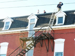 Storm Winters, front left, and Jolene Kay-Slark talk to workers from Brockville Roofing outside the Perth Street building that was damaged by fire last week. (RONALD ZAJAC/The Recorder and Times)