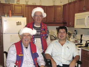 On December 21, Devon Lions Club members Bill Bates and Ian Sinclair (in back) brought Christmas cheer to Don Yuhasz. Don was the recipient of an electric wheel chair. The Devon Lions have a loan service for local residents who may be in need of medical equipment.